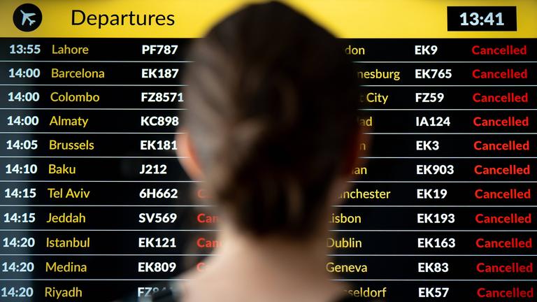 Eine Frau steht vor der Anzeigetafel an einem Flughafen.