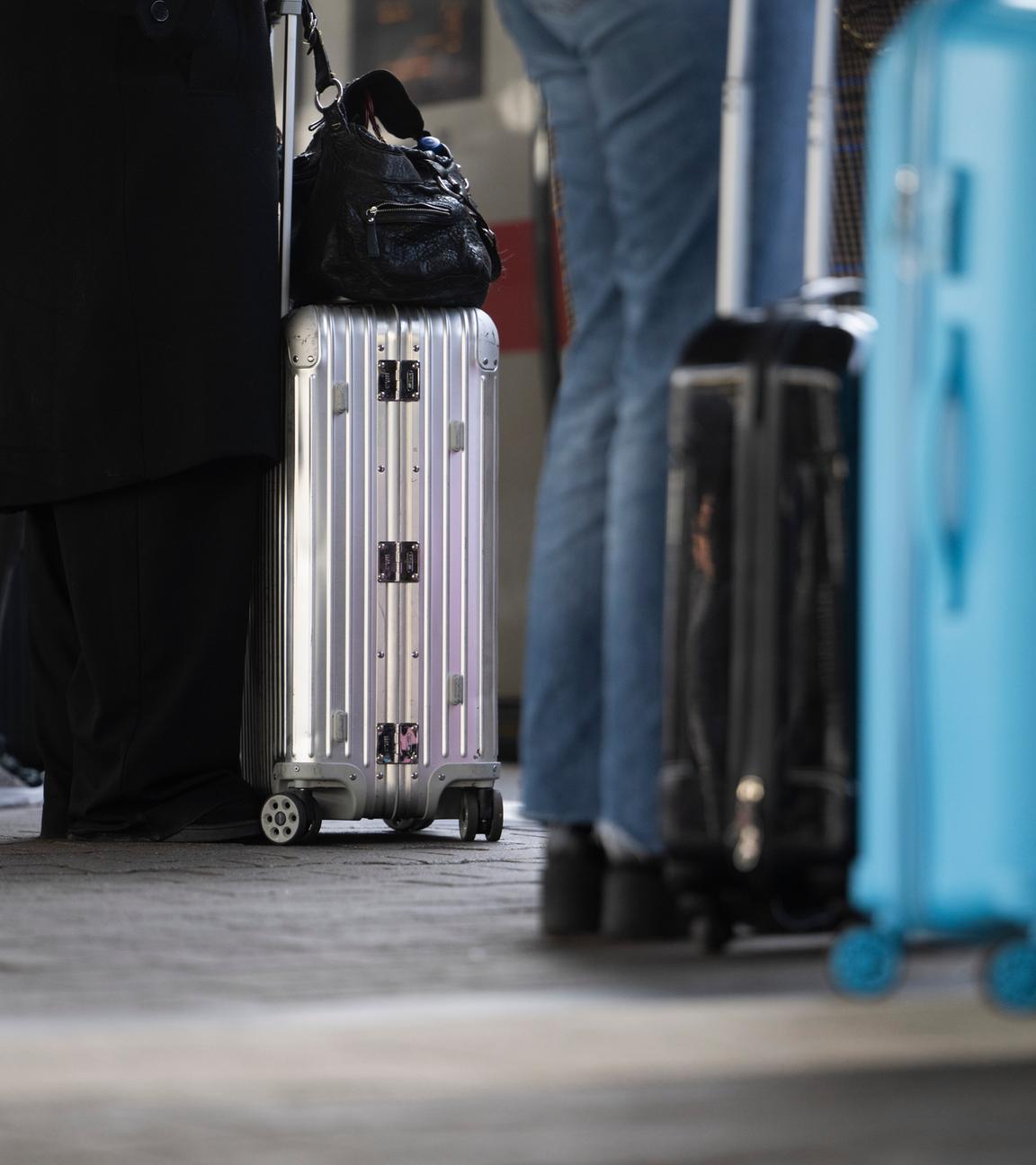 Reisende stehen mit ihrem Gepäck an einem Gleis am Hauptbahnhof.