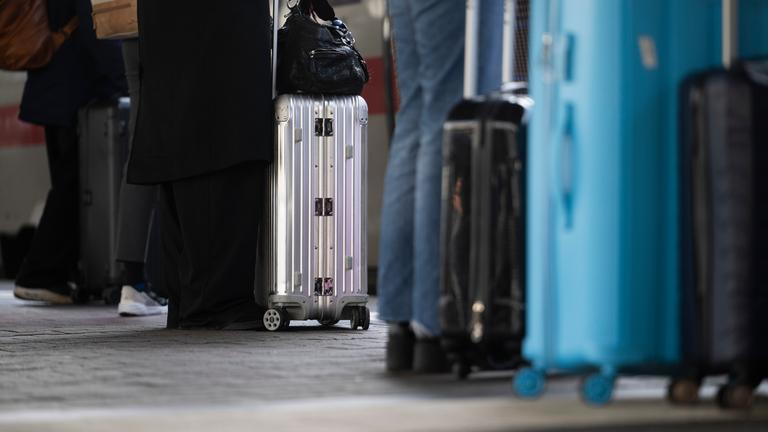Reisende stehen mit ihrem Gepäck an einem Gleis am Hauptbahnhof.