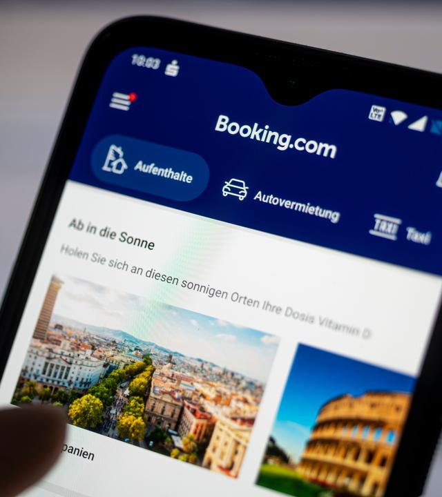 Auf einem Smartphone ist die App des Reiseportals Booking.com zu sehen.