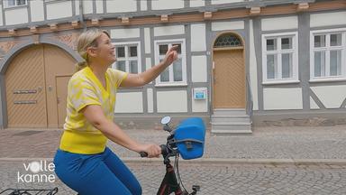 Marina Wenk fährt mit Fahrrad durch eine Altsadt und freut sich