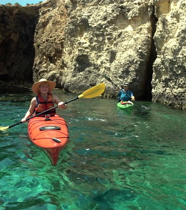 Reporterin Marina Wenk fährt auf einem Kanu durch  Felsen in türkisem Wasser 