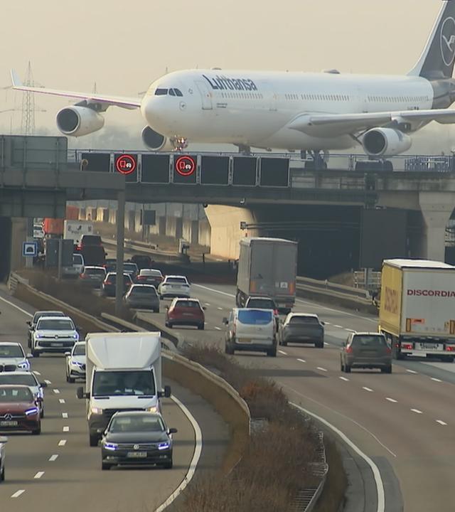 Flugzeug landet auf Landebahn, die über einer gut befahrenen Autobahn gelegen ist