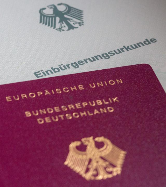 Einbürgerungsurkunde im Hintergrund mit deutschem Pass im Vordergrund