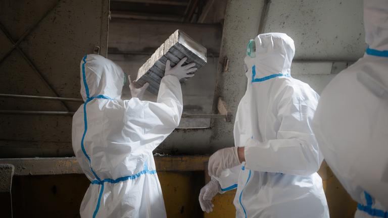 Polizisten in Schutzanzügen verladen sichergestelltes Kokain.