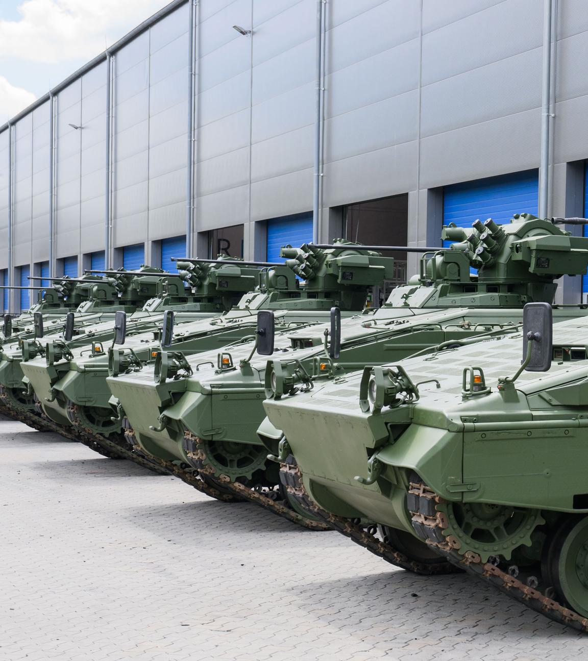 Wieder aufbereitete Marder-Schützenpanzer stehen vor einer Halle.