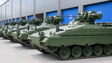 Wieder aufbereitete Marder-Schützenpanzer stehen vor einer Halle.