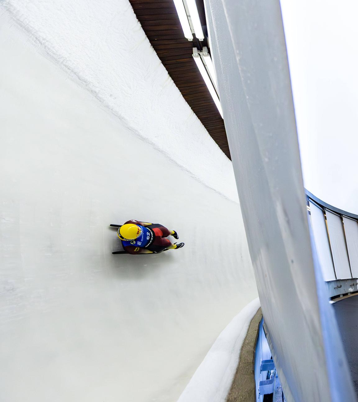 Eine Person fährt in einem Schlitten eine Rodelbahn entlang.