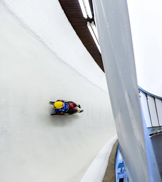 Eine Person fährt in einem Schlitten eine Rodelbahn entlang.