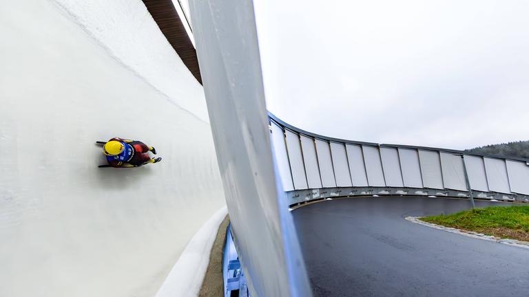Eine Person fährt in einem Schlitten eine Rodelbahn entlang.