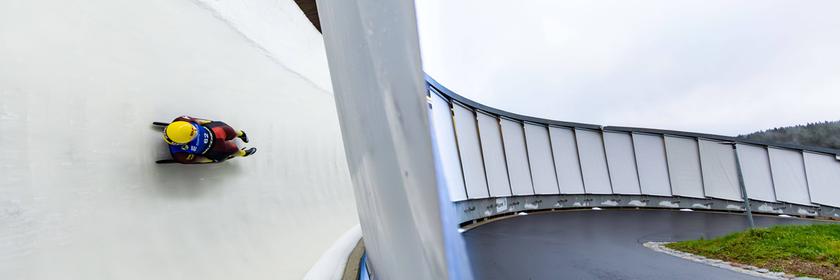 Eine Person fährt in einem Schlitten eine Rodelbahn entlang.