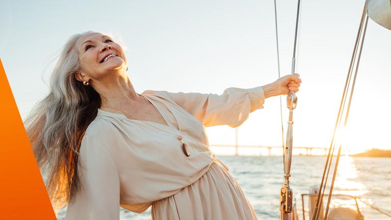 Freizeit in der Rente: Frau segelt mit Schiff in den Sonnenuntergang