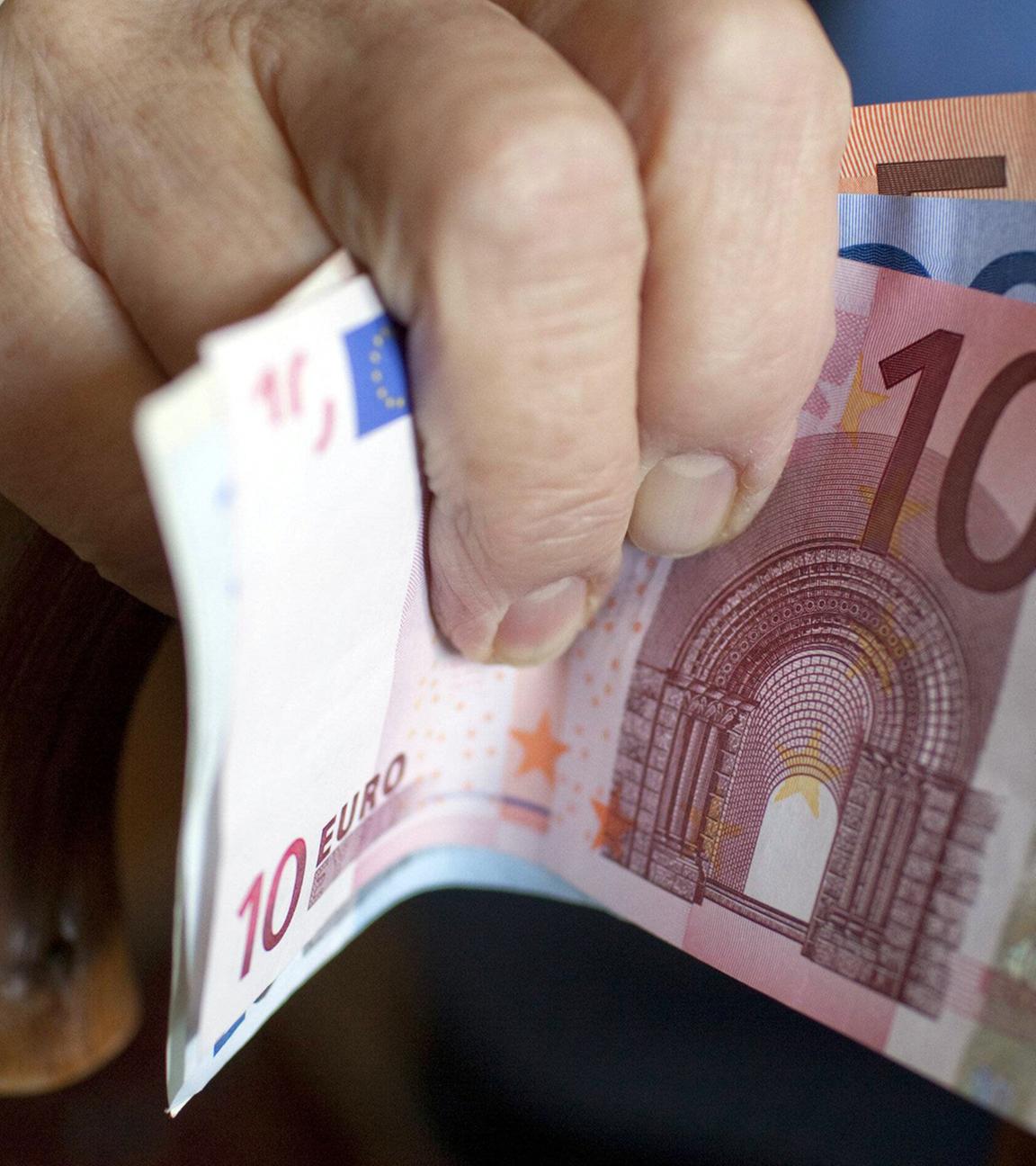 Eine Seniorin hält Geldscheine in der Hand.