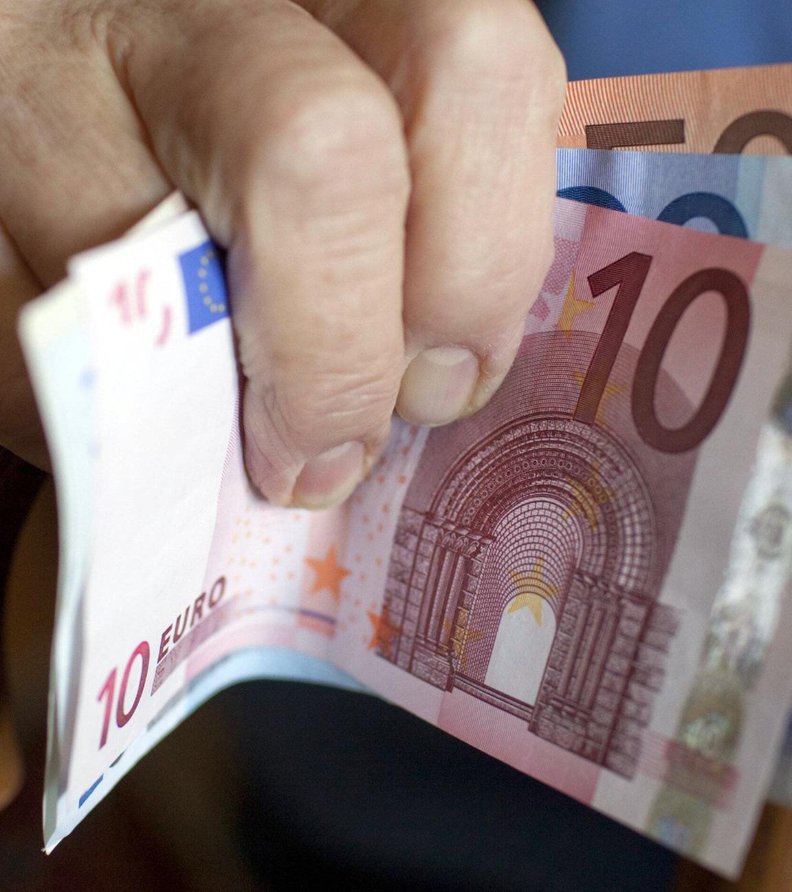 Eine Seniorin hält Geldscheine in der Hand.