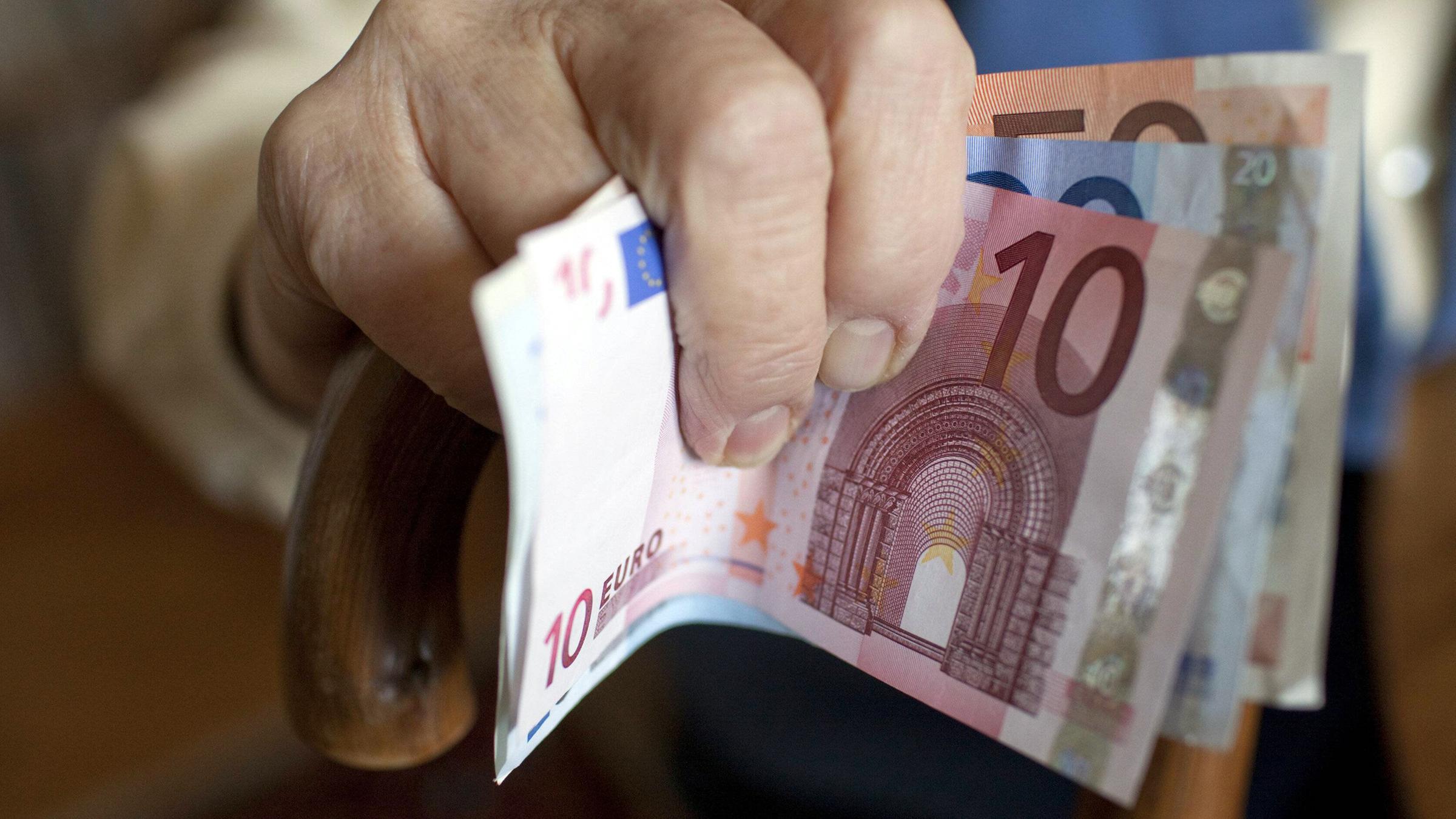 Eine Seniorin hält Geldscheine in der Hand.