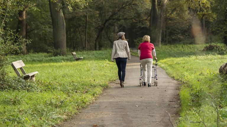 Drei Kinder und drei ältere Menschen sitzen an einer Bushaltestelle