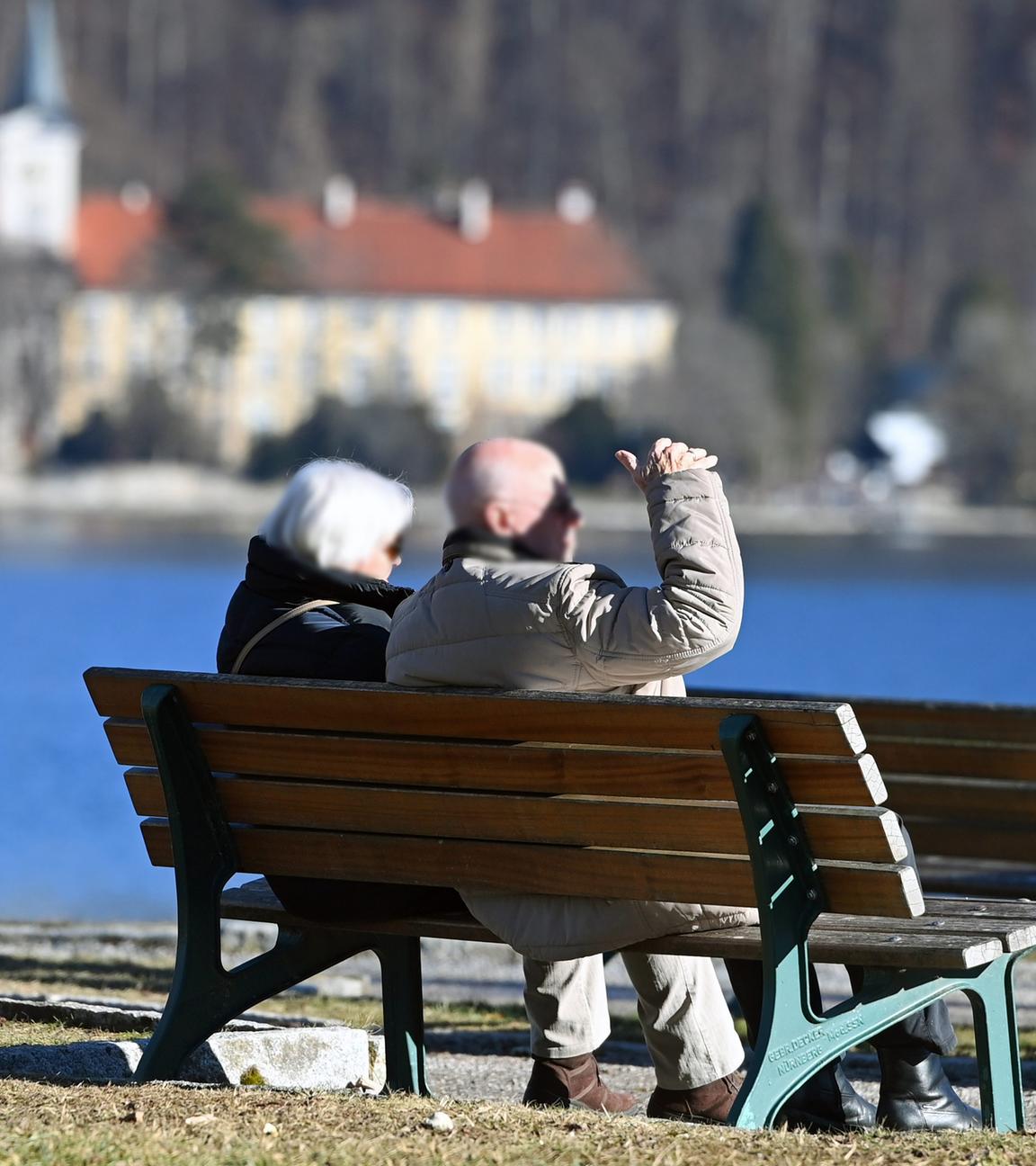 Älteres Ehepaar sitzt auf einer Parkbank am Tegernsee