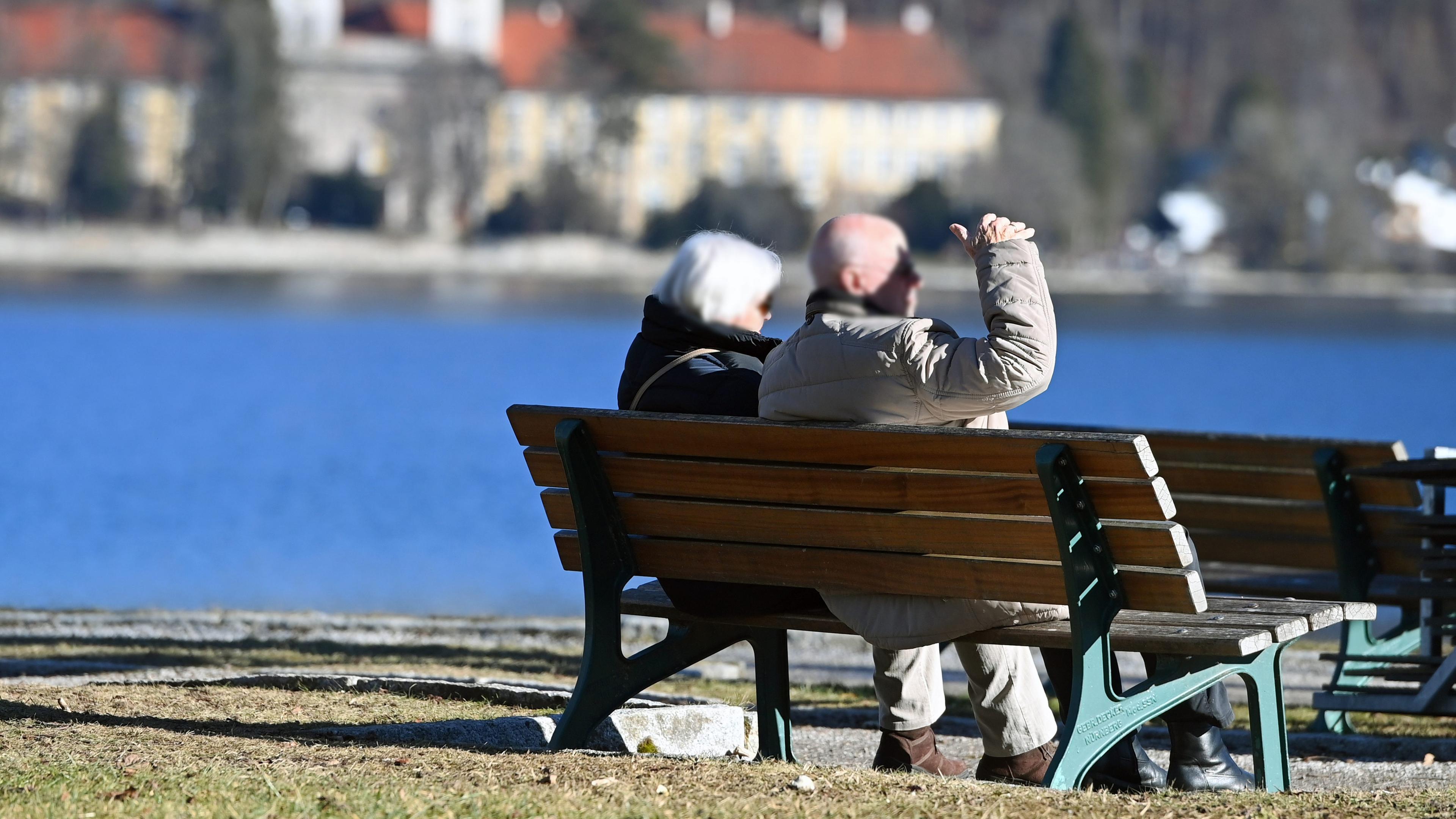 Älteres Ehepaar sitzt auf einer Parkbank am Tegernsee