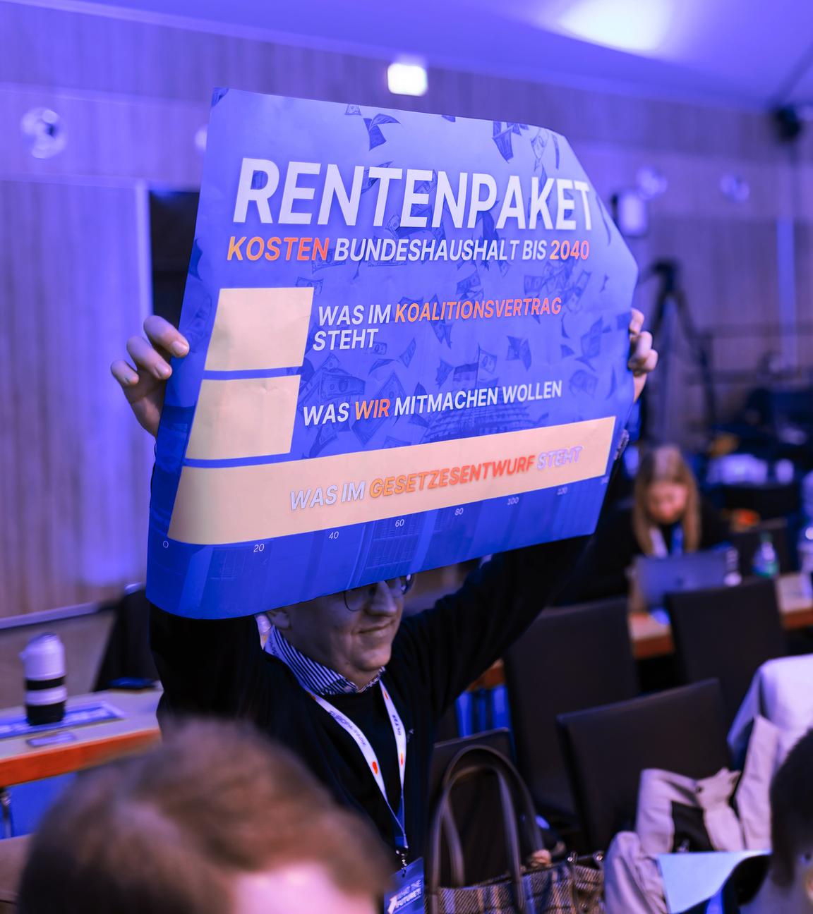 Ein Teilnehmer hält beim Deutschlandtag der Jungen Union ein Plakat zum Rentenpaket hoch. 