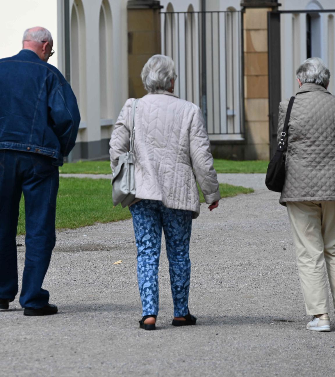 Drei Rentner spazieren durch den Park am Schloss Borbeck in Essen.