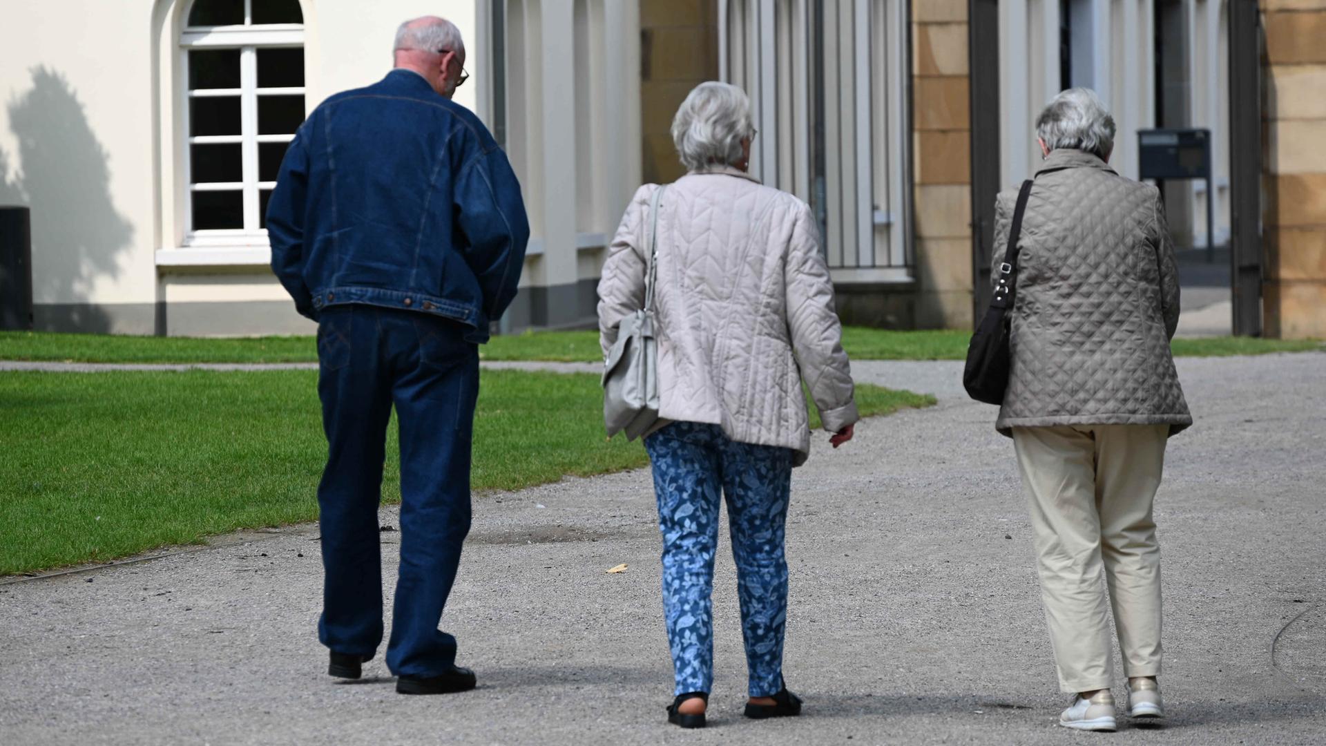 Drei Rentner spazieren durch den Park am Schloss Borbeck in Essen.