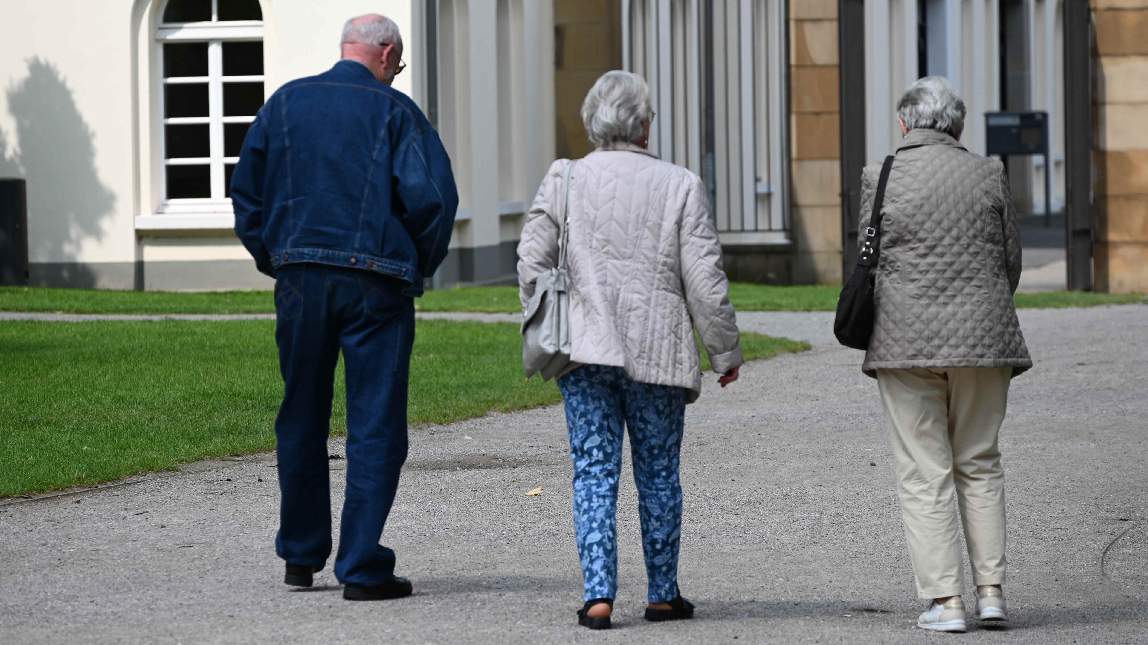 Drei Rentner spazieren durch den Park am Schloss Borbeck in Essen.