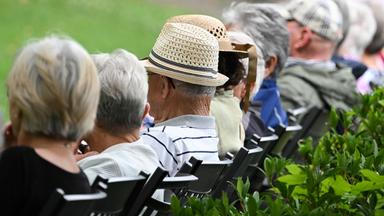 Ältere Menschen sitzen in einem Kurpark, am 15.07.2025 in Bad Kreuznach, in einer Reihe.