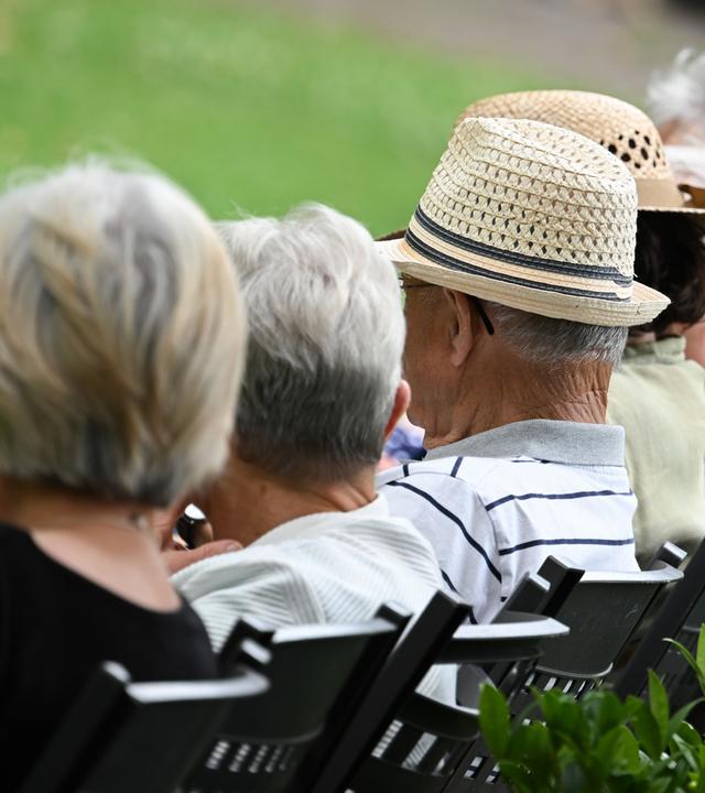 Ältere Menschen sitzen in einem Kurpark, am 15.07.2025 in Bad Kreuznach, in einer Reihe.