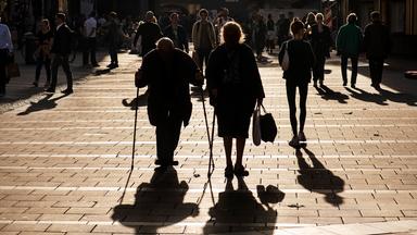 Ein Rentnerehepaar spaziert, in der Herbstsonne als Gegenlicht, auf dem Münchner Marienplatz am 28.10.2022.