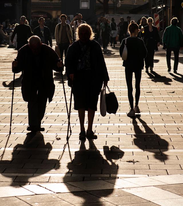 Ein Rentnerehepaar spaziert, in der Herbstsonne als Gegenlicht, auf dem Münchner Marienplatz am 28.10.2022.