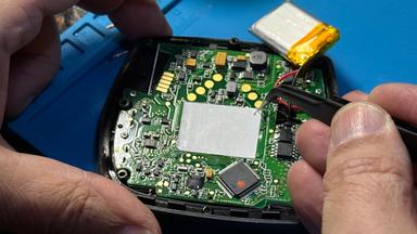 Die Platine eines E-Bike-Displays wird mit einer Pinzette repariert