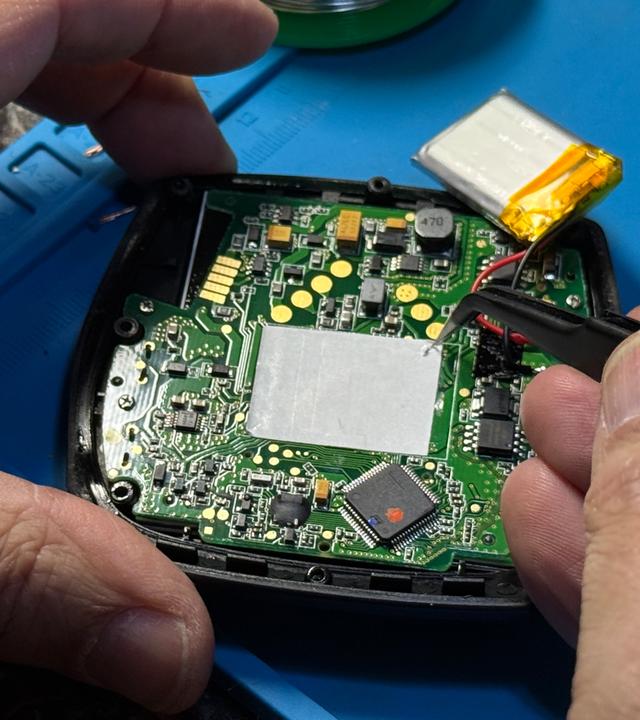 Die Platine eines E-Bike-Displays wird mit einer Pinzette repariert