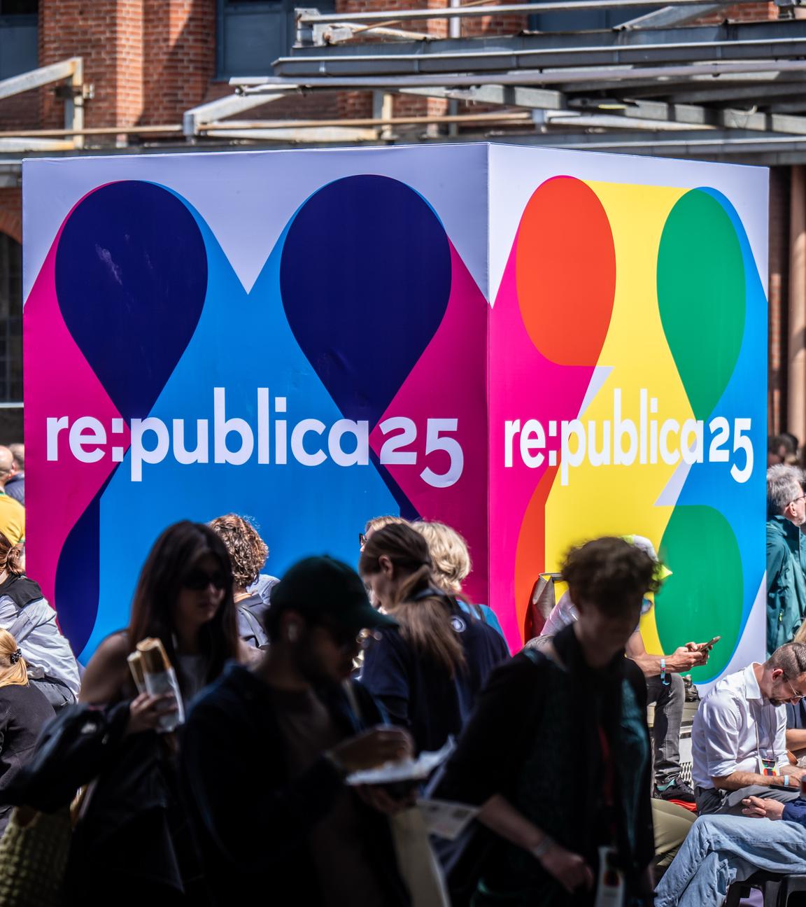 Besucher der Medienkonferenz Re:publica sitzen an einem Logo-Aufsteller am Veranstaltungsort «Station Berlin».