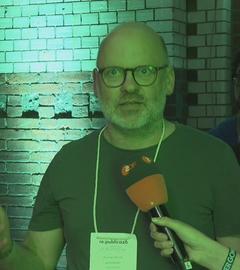 Mann in grünem Licht bei re:publica mit ZDF-Mikrofon vor sich.