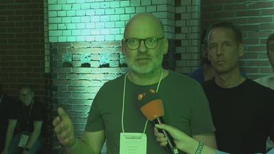 Mann in grünem Licht bei re:publica mit ZDF-Mikrofon vor sich.