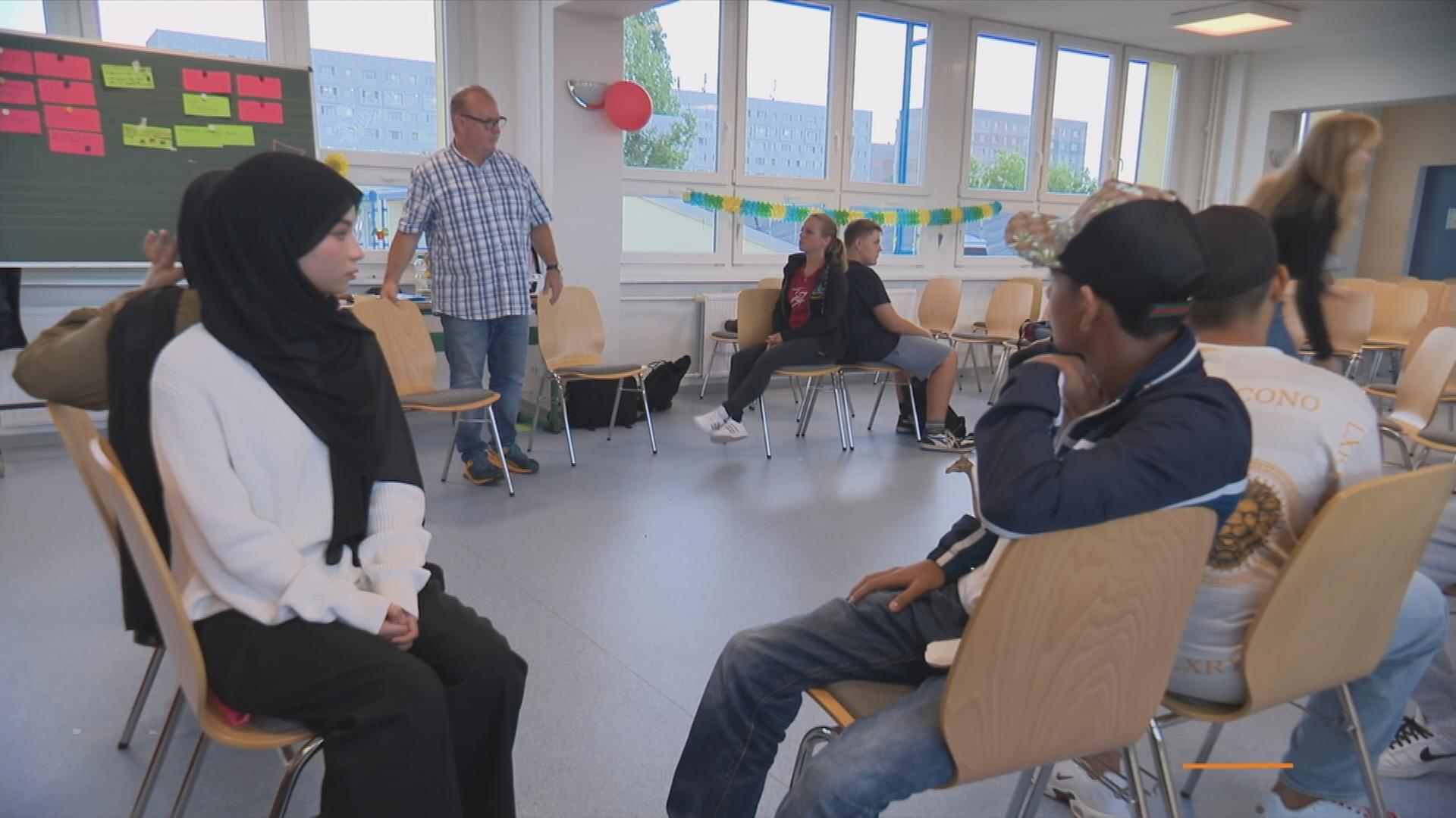 Schüler sitzen mit sogenannten Respekt-Coaches bei Übung in Zweiergruppen Rücken an Rücken im Klassenraum