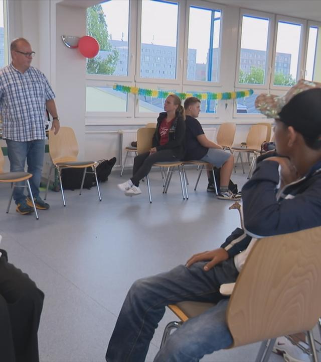 Schüler sitzen mit sogenannten Respekt-Coaches bei Übung in Zweiergruppen Rücken an Rücken im Klassenraum