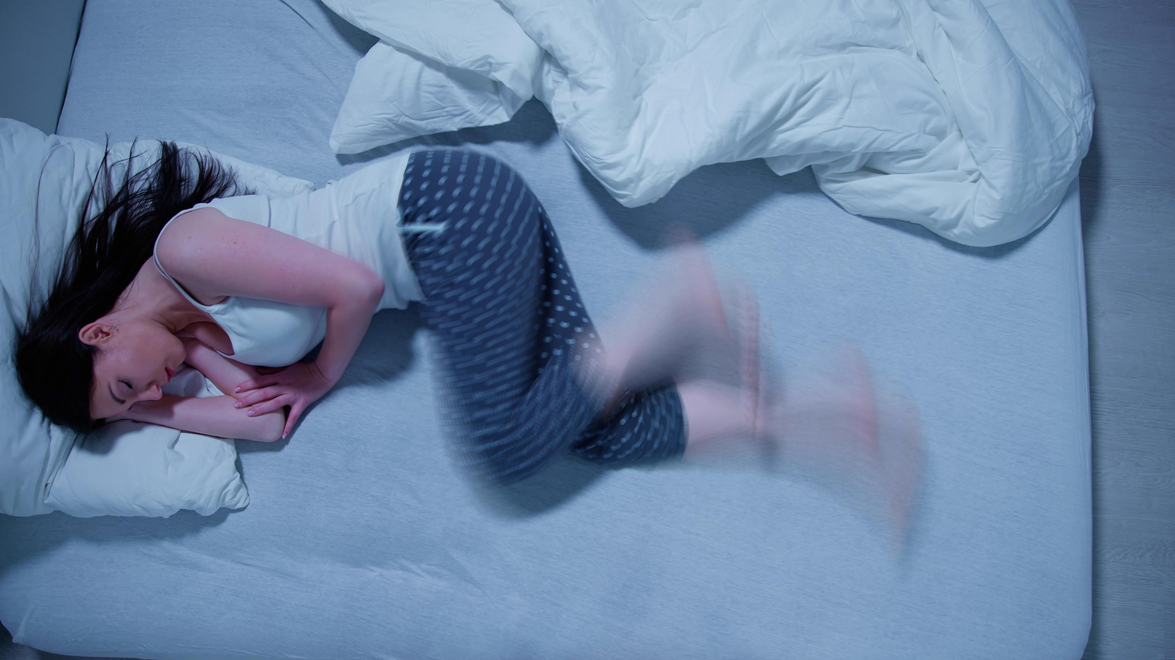 Eine Frau mit RLS , dem Restless Legs Syndrom, schläft in ihrem Bett.