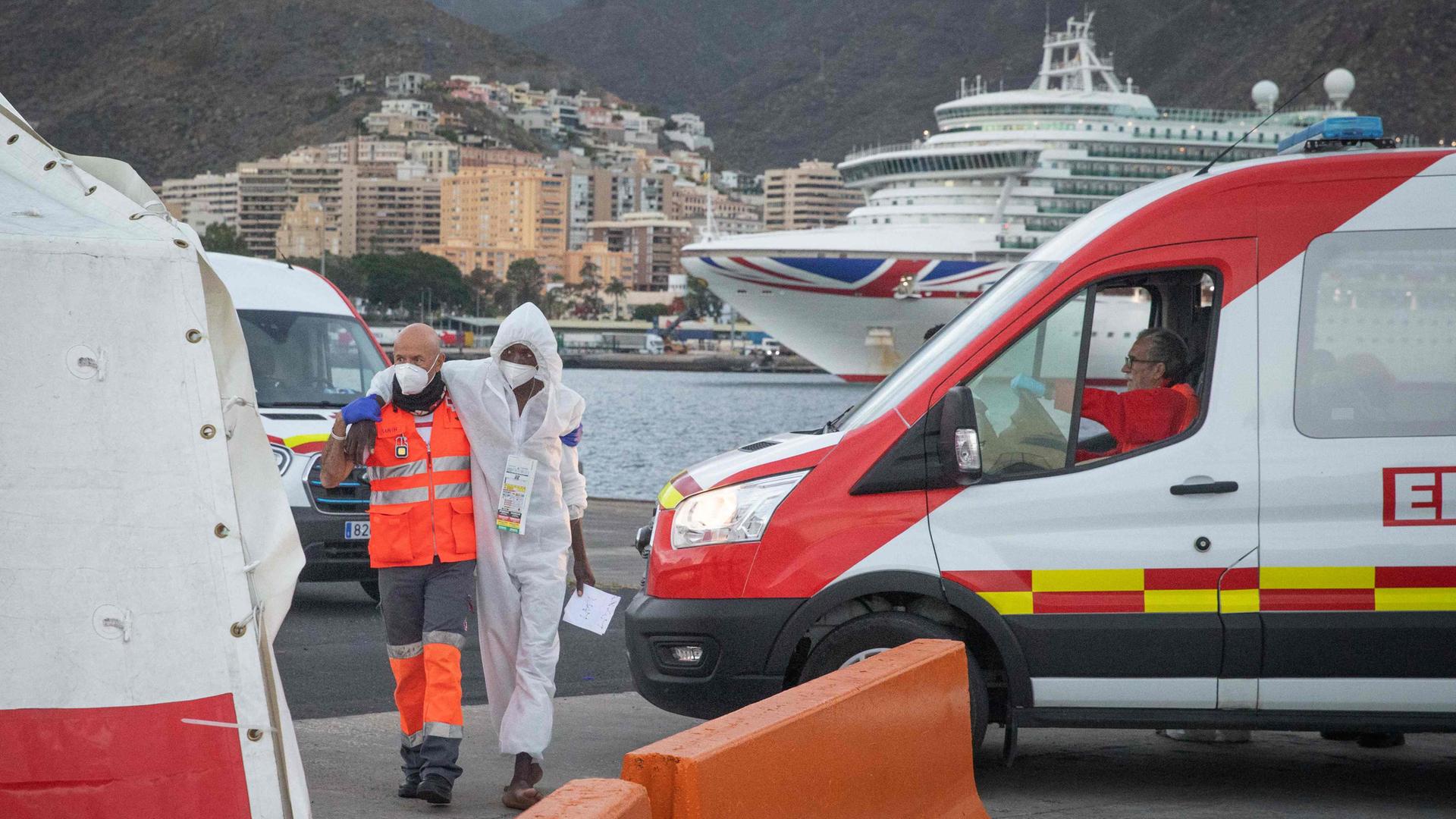 Ein Helfer unterstützt einen Migranten während er zu einem Zelt des Roten Kreuz im Hafen von Teneriffa geht.