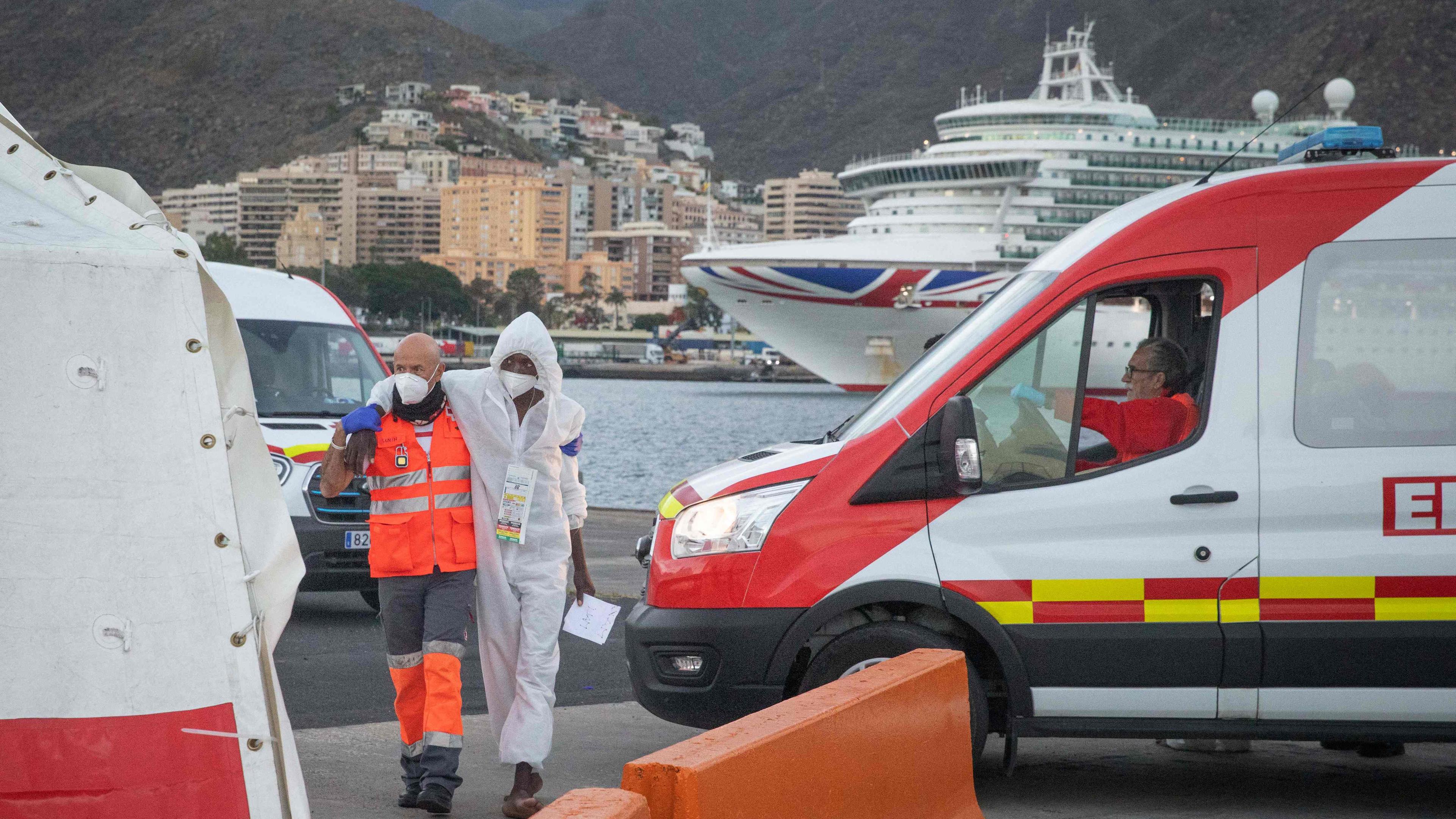Ein Helfer unterstützt einen Migranten während er zu einem Zelt des Roten Kreuz im Hafen von Teneriffa geht.