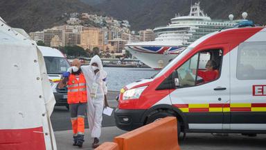 Ein Helfer unterstützt einen Migranten während er zu einem Zelt des Roten Kreuz im Hafen von Teneriffa geht.