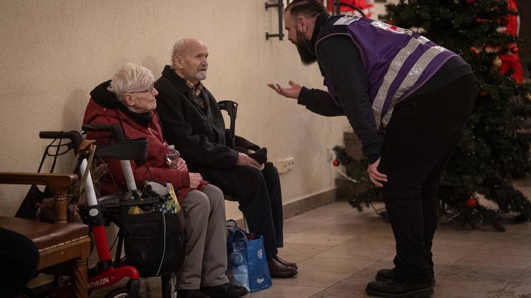 Ein Rettungshelfer unterstützt ältere Bewohner in einem provisorischen Betreuungszentrum im Bezirk Zehlendorf, während die Stromausfälle im Südwesten Berlins andauern.
