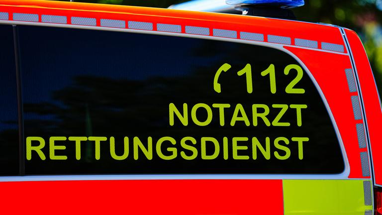 Ein Teil eines Rettungswagens mit Blaulicht und der Aufschrift 112, Rettungsdiesnst, Notarzt ist zu sehen.
