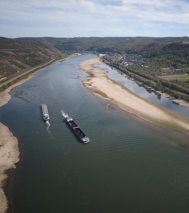 Luftaufnahme zweier Transportschiffe auf dem Rhein, am Rand sind große Sandbänke zu erkennen.