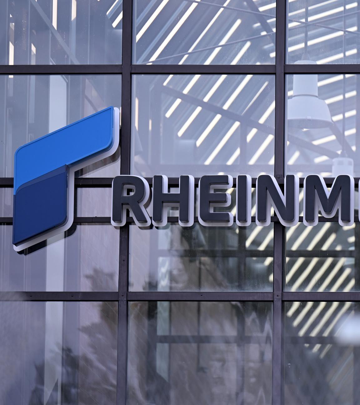  Das Logo des Rüstungskonzerns Rheinmetall ist hinter einem Zaun (verschwommen im Vordergrund) am Eingang eines Rheinmetall-Werks zu erkennen. 
