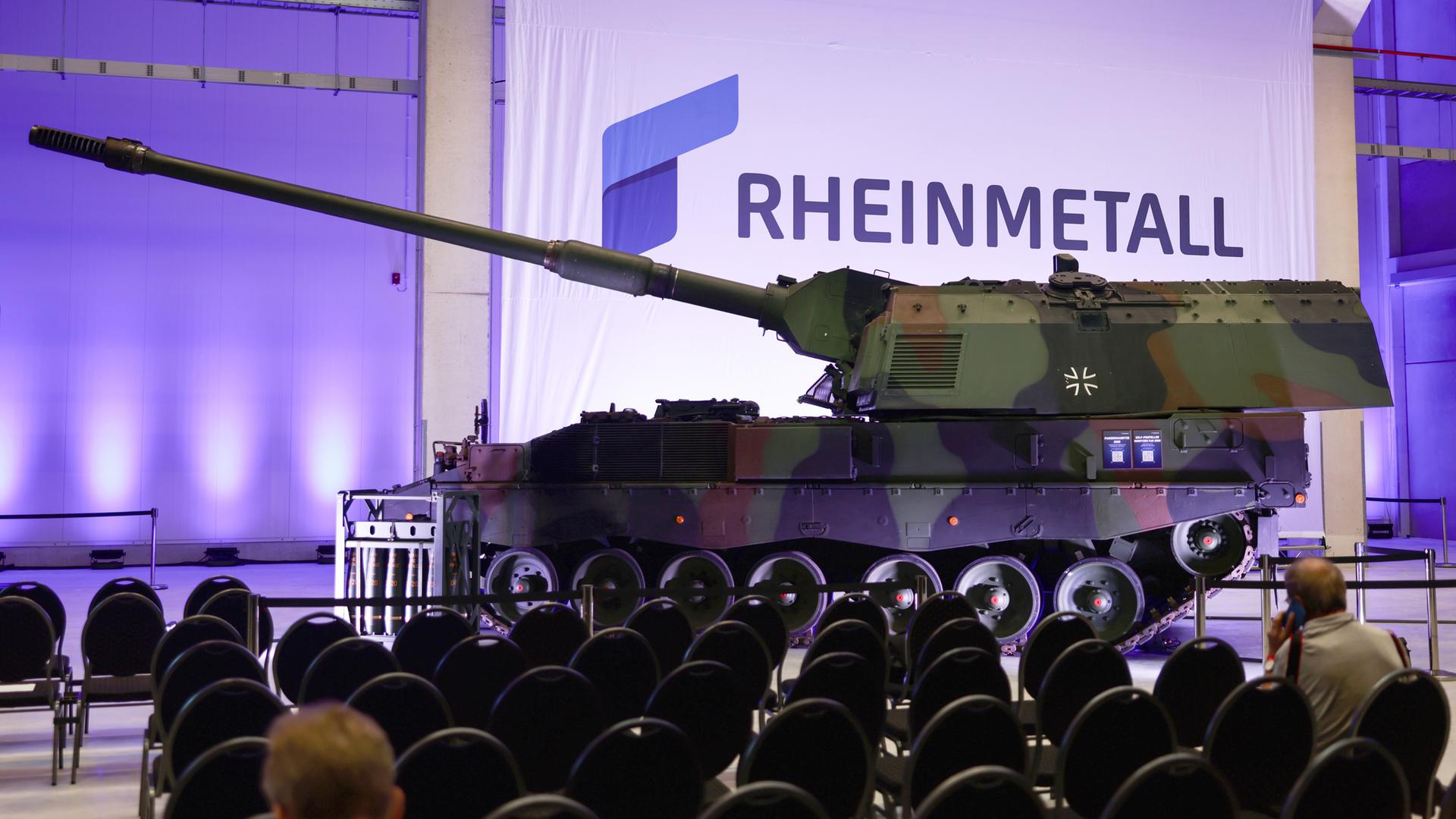Das Firmenlogo hinter einem Haubitzenpanzer vom Typ 2000 während der offiziellen Eröffnungszeremonie eines neuen Rheinmetall-Munitionswerks in Unterlüss