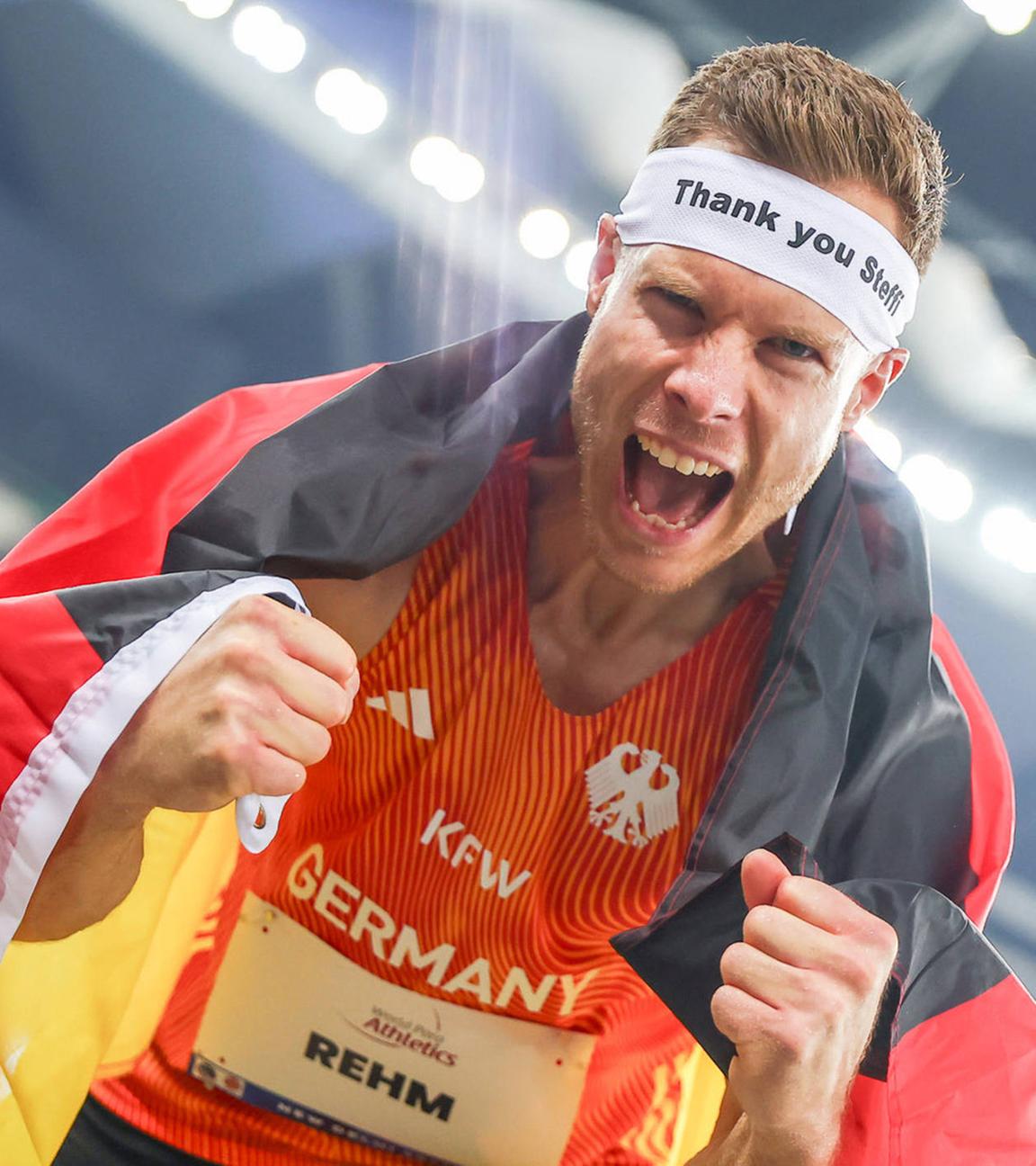 Markus Rehm vom Team Deutschland mit deutscher Flagge nach dem Weitsprung der Männer T64, trägt ein Stirnband mit der Aufschrift „Thank you Steffi“ bei den World Para Athletics Championships 2025 in Neu-Delhi, Indien, am 03.10.2025.