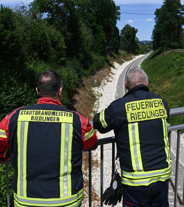 Die Feuerwehrmänner und Stefan Kuc (l) und Thomas Steinhardt (r) stehen an einer Unfallstelle, an der ein Jahr zuvor ein Zug entgleist war.