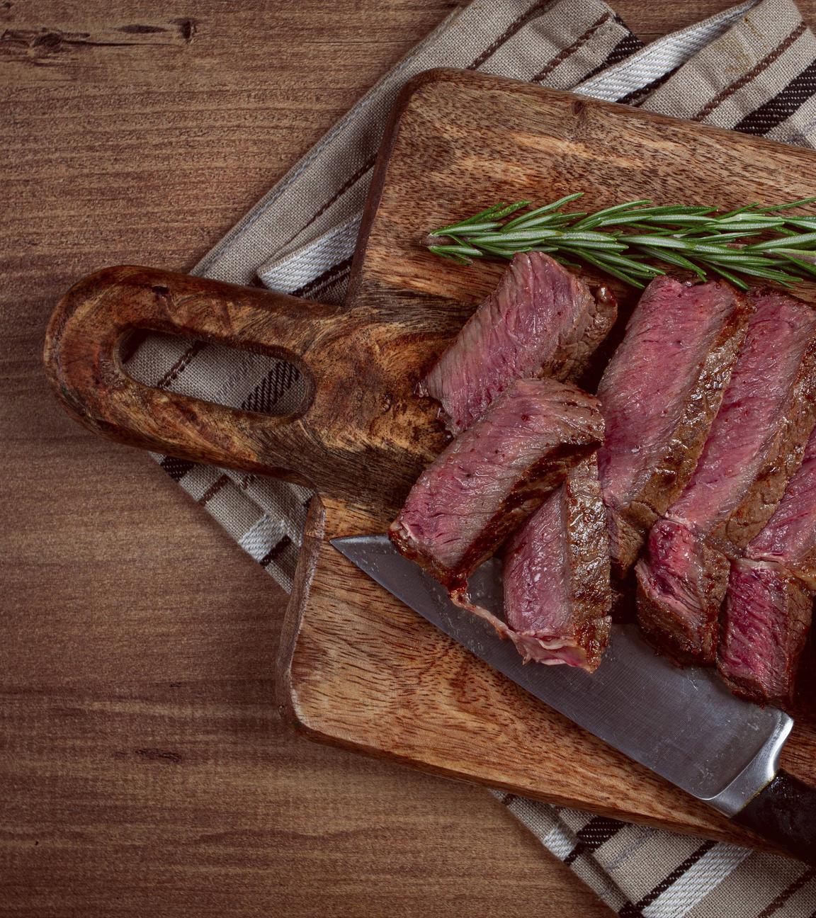 Ein in Scheiben geschnittenes Rindfleischsteak auf einem Schneidebrett.