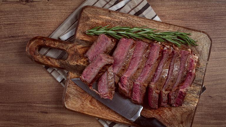 Ein in Scheiben geschnittenes Rindfleischsteak auf einem Schneidebrett.